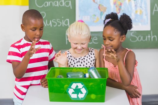 School Kids Looking Recycle Logo Box In Classroom