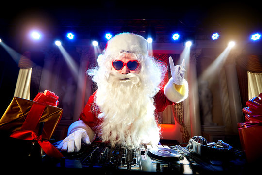 Dj Santa Claus mixing at the party Christmas, raised his hand up