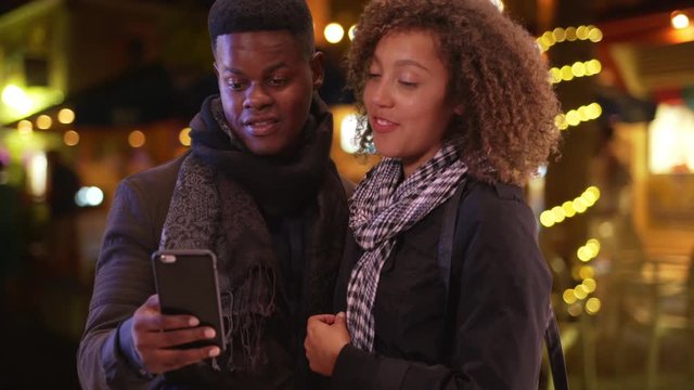 Millennial black couple call a taxi with their smart phone. Young African American man and woman call a ride
