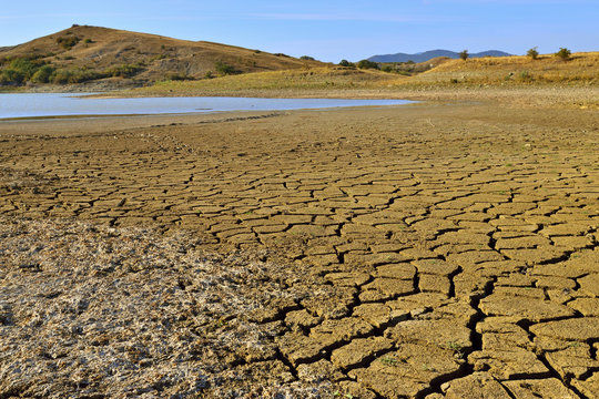 Shore of drying up of lake is covered with cracked mud.
