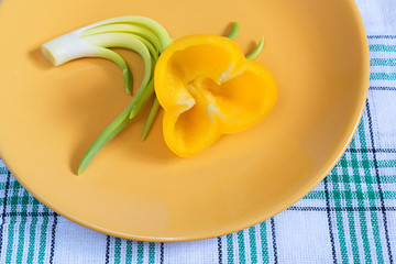 Yellow pepper and green onions on plate.