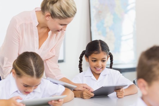 Teacher teaching school girl on digital tablet