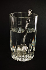 Vaso de agua y cuchara sobre fondo negro