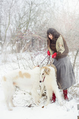 girl with two greyhounds in the winter, falling snow