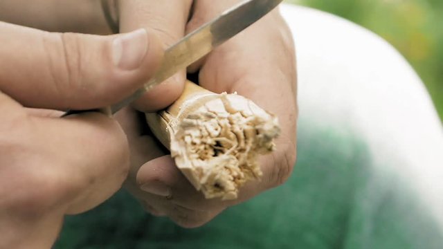 Craftsman hands carving wood rod with a knife. Closeup macro shot. DIY and craftsmanship handmade authentic concept.