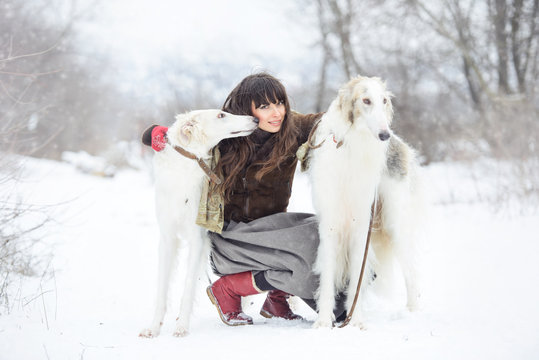 girl with two greyhounds in the winter, falling snow