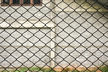 Rusty steel chain link or wire mesh as boundary wall. There is still concrete block wall behind the...