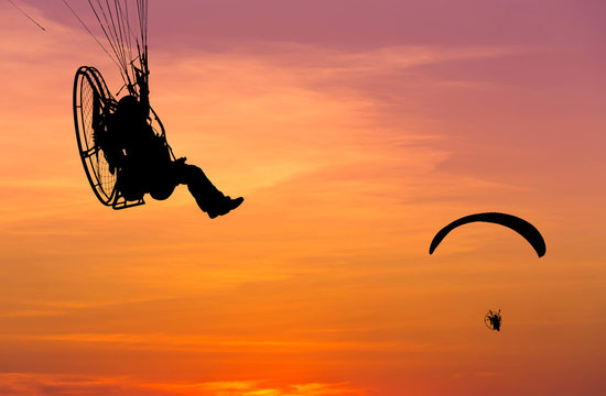 paragliders flying with paramotor on sunset