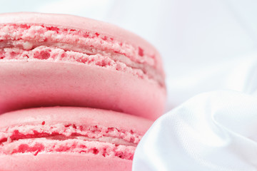 tasty pink strawberry macaroons on white silk background