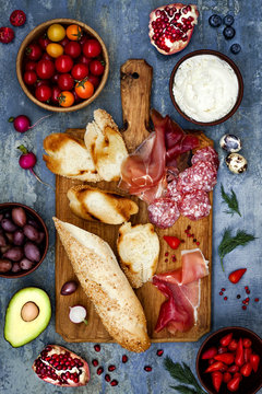 Brushetta or authentic traditional spanish tapas set for lunch table. Sharing antipasti on party or picnic time over blue rustic background. Top view.