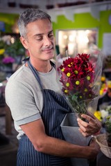 Male florist holding bunch of red sunflower in vase