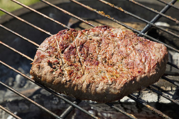 Grilled beef steak cooking on barbecue grill