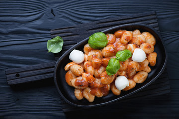Gnocchi alla Sorrentina in a frying pan, black wooden background