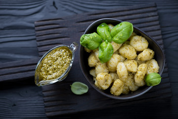 Italian gnocchi served with pesto on a black wooden background