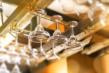 Closeup image of glasses hanging on rack at bar background