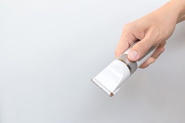 Hand holding hair clippers on grey background