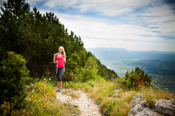 Naklejka premium Trekking - woman hiking in mountains on a calm sumer day