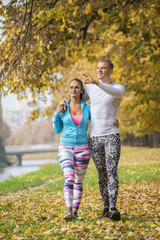 Beautiful young couple walking together in the park. Autumn environment.