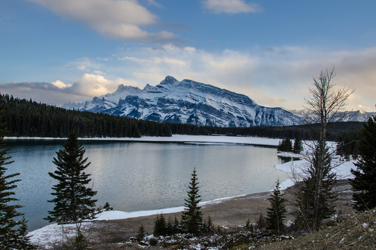 Snow covered mountains in Banff with ice-rimmed lake in foreground