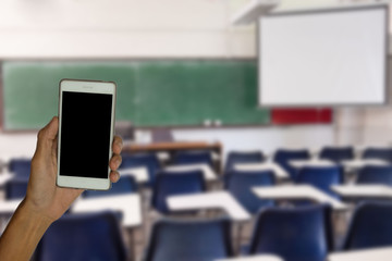 hand of child holding mobile phone with blur student learning in classroom background