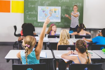 School girl raising hand in classroom