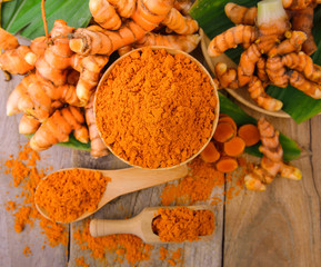 dry turmeric in a wood bowl  with leaf and fresh turmeric on tab
