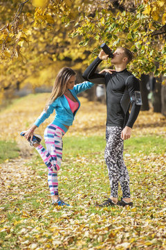 Beautiful young couple cooling down after running in the park. Autumn environment.