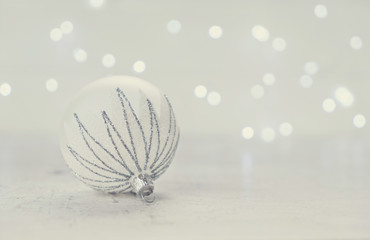 Christmas scene with one white and silver ball and christmas lights in background, retro toned