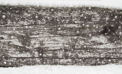 old dark wooden fence in snow. wood background with snowflakes.  planks texture, winter, snowfall