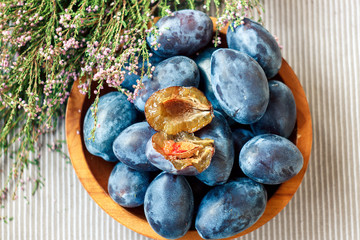 Fresh organic plums in wooden bowl 