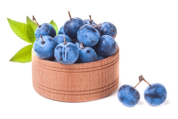 blackthorn berries with leaves in a wooden bowl isolated on white background