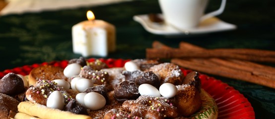 Detail of delicious Christmas cookies with cup of coffee on a table with candle on white tone