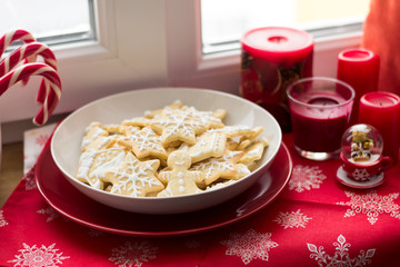 Christmas decoration: gingerbread cookies, candies, toys and burning red candles on windowsill