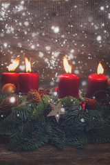 Evergreen fir tree advent garland with four red burning candles on wooden bakcground with snow