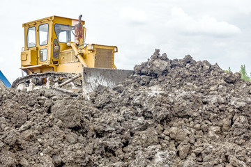 Heavy earthmover construction machine is moving earth at buildin
