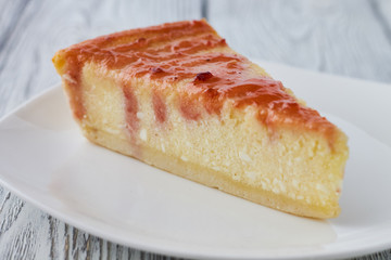 Slice of the New York cheesecake on a white plate on a wooden background