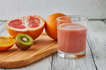 he juice of a grapefruit, kiwi, an orange on a wooden background