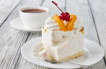 Cake dessert with peach, cherry and hot chocolate on a wooden background