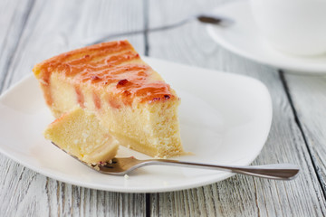Slice of the New York cheesecake on a white plate on a wooden background