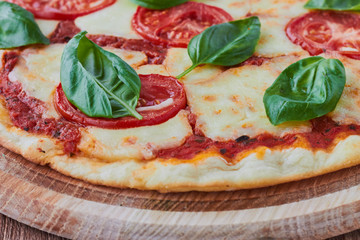 Pizza Margherita with tomatoes, mozzarella and basil on a wooden background сlose up.