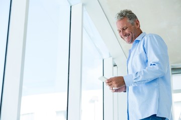Naklejka na ściany i meble Low angle view of smiling man using phone