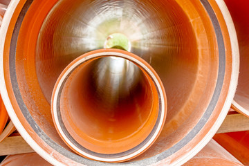 PVC orange tubes, pipes are stacked in a pile at building site,
