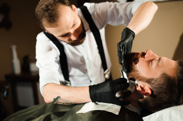 Master cuts hair and beard of men in the barbershop