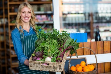 Smiling staff holding a basket of fresh vegetables 