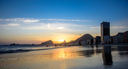 Fototapeta na wymiar Beautiful sunset, the edge of Atlantic ocean and silhouette of the ball in the sky at Copacabana beach, Rio de Janeiro, Brazil