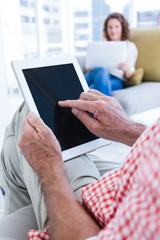 Midsection of man touching tablet at home