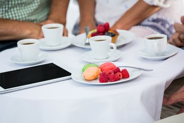 Cropped image of friends sitting by table in restaurant