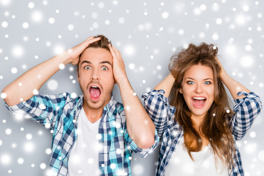 Surprised man and woman screaming and touching hair on snowy bac