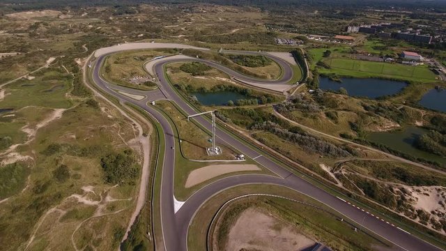 Aerial of curvy part of the Zandvoort racing circuit in Holland. A few cars practice on the track.