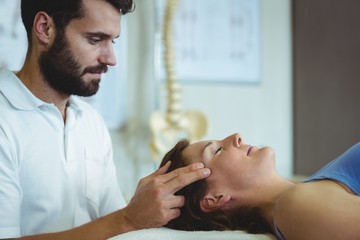 Obraz na płótnie Canvas Physiotherapist giving head massage to a woman